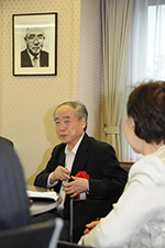 Dr. Kobayashi sits below a portrait of Mikio Mizuta before his lecture
