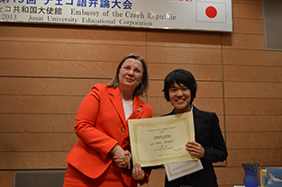 表彰式で、1位の賞状を手に大使と握手する槍田さん